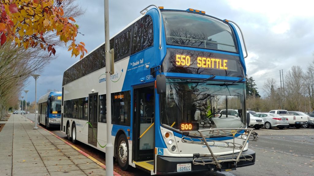 Picture of a double decker bus with fall leaves in the front view. 
