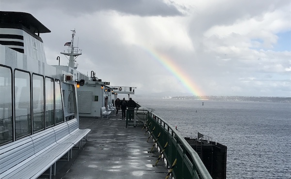 Photo from a ferry deck with a rainbow up ahead.