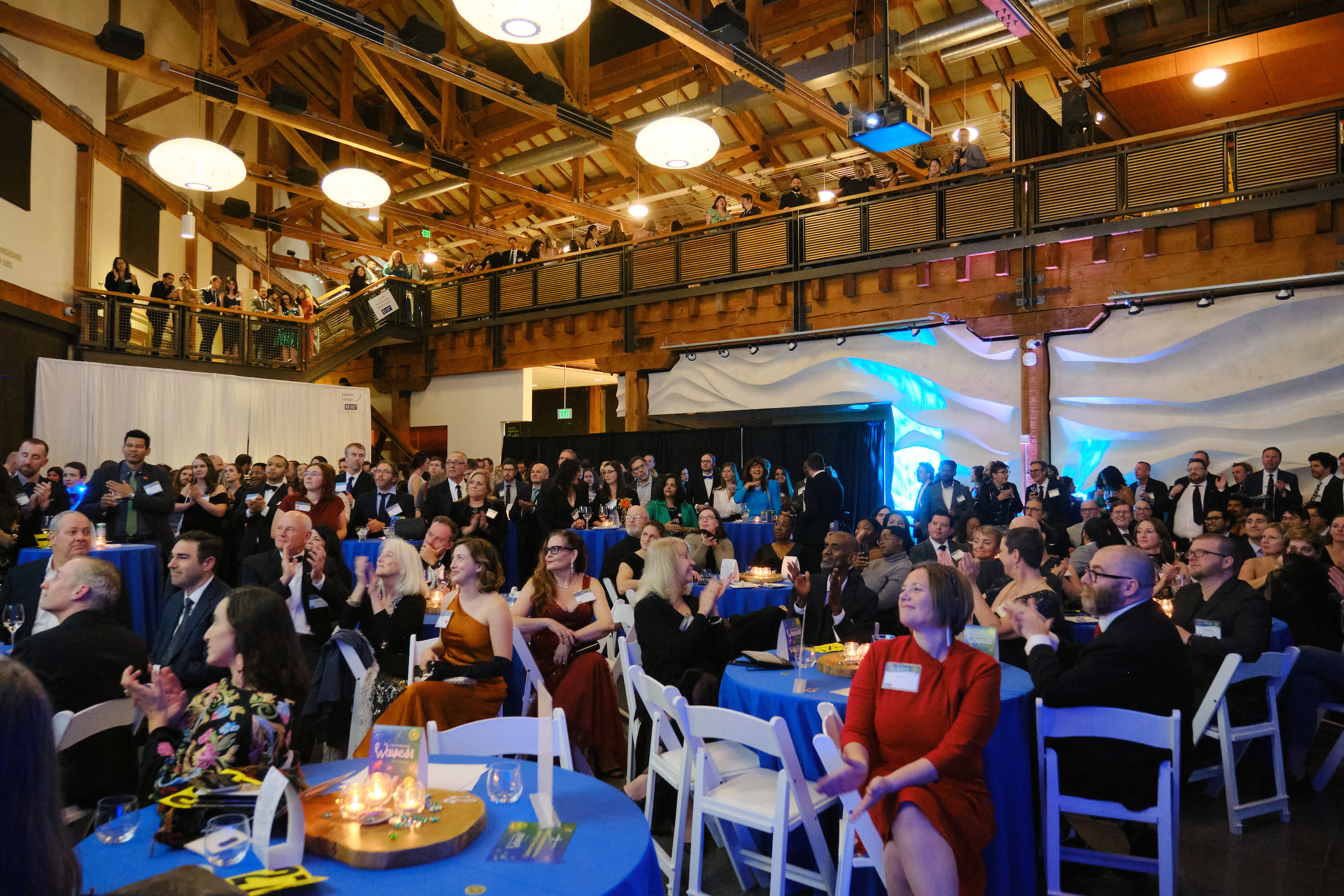 People gather in the Seattle Aquarium's Puget Sound Hall for Tuxes & Trains 2023. 