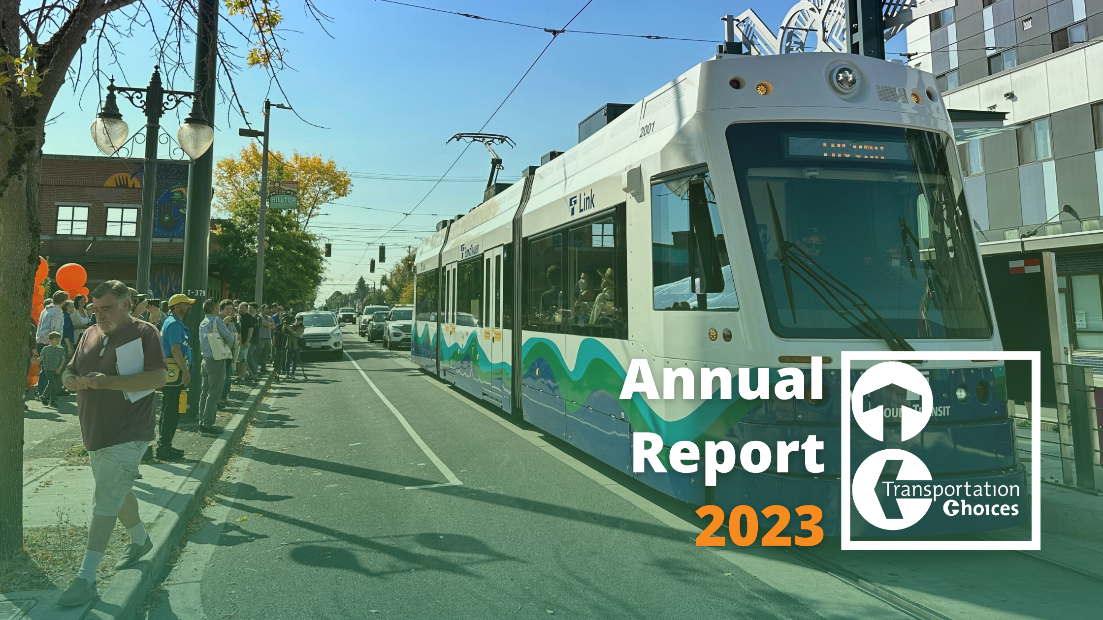 Photo of the new Hilltop Light Rail Extension in Tacoma, with people celebrating with balloons on the side of the street. Text: Annual Report 2023, with the Transportation Choices Coalition Logo.