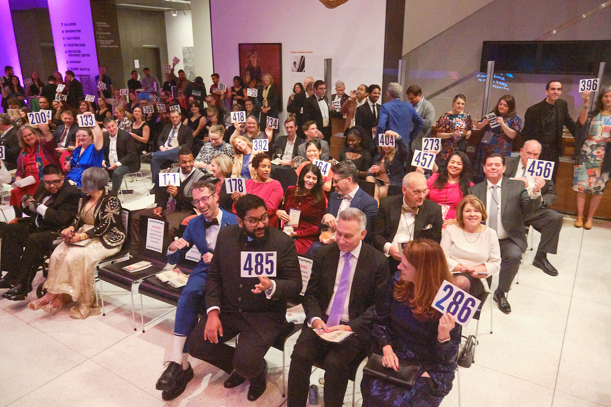 Guests hold up their bidder numbers to donate to TCC.