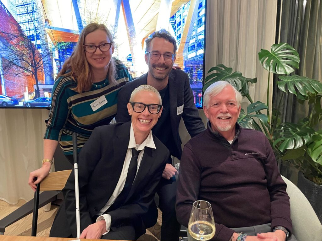Four people pose smiling for a photo together.