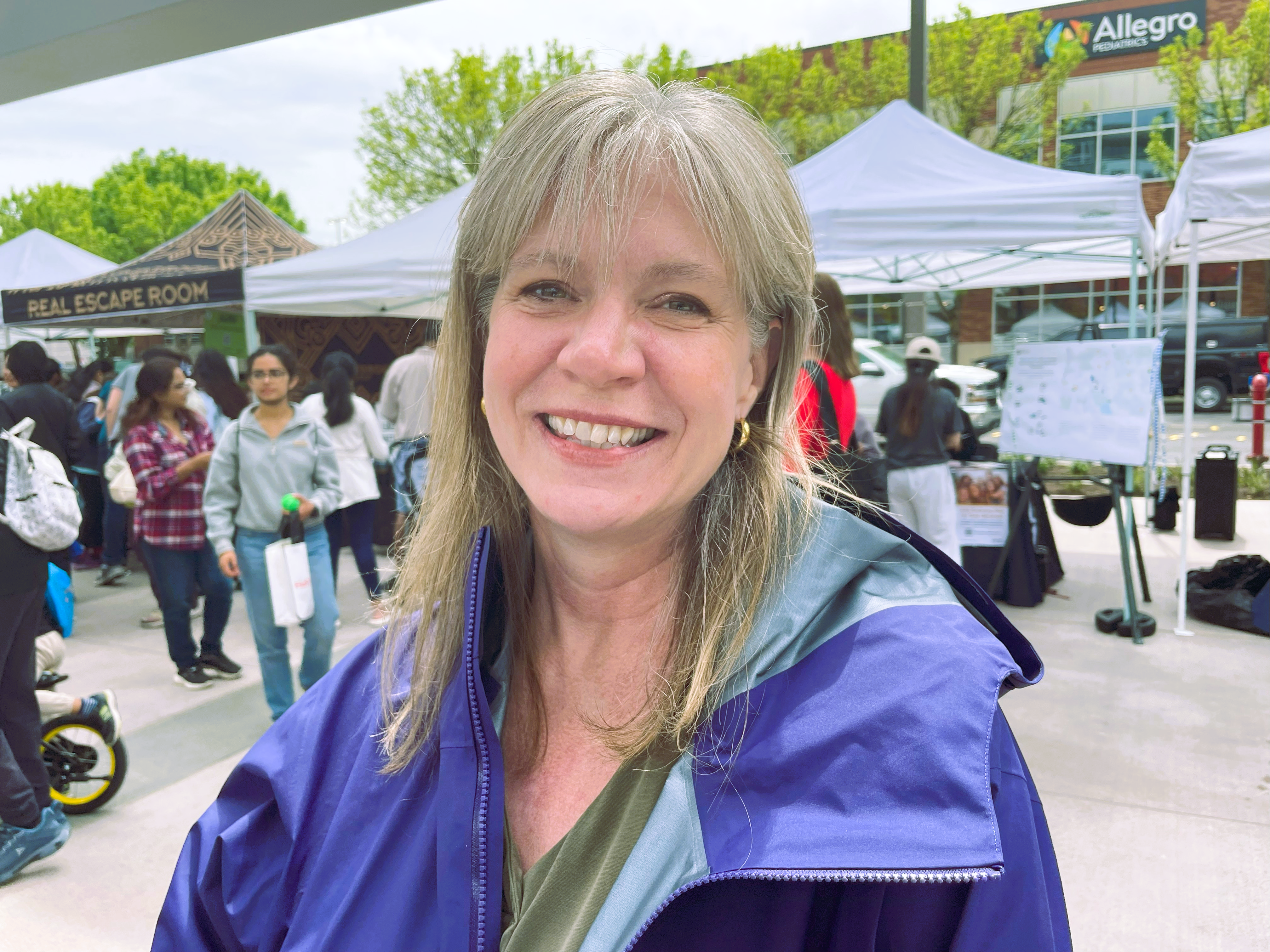 Heather-Downtown-Redmond A woman with greyish brown hair smiles for the camera.