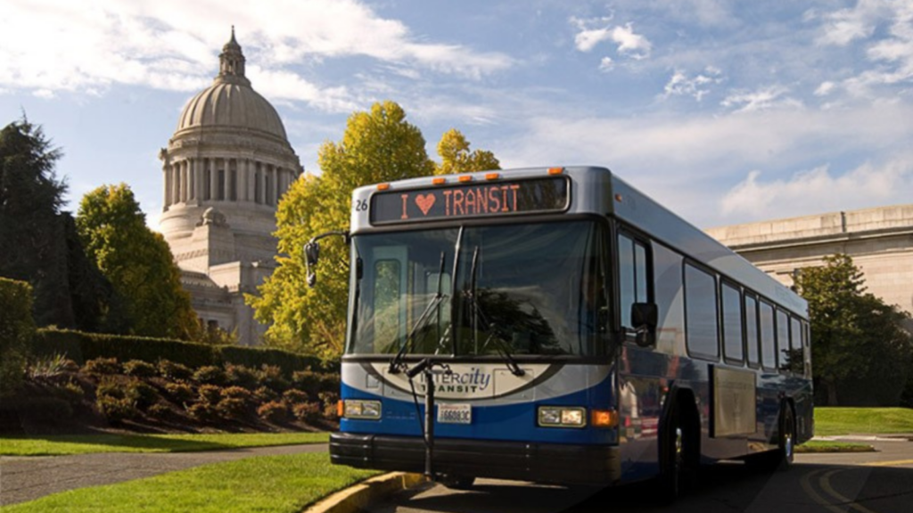 Bus parked in front of government building with text on the front that says "I love transit"