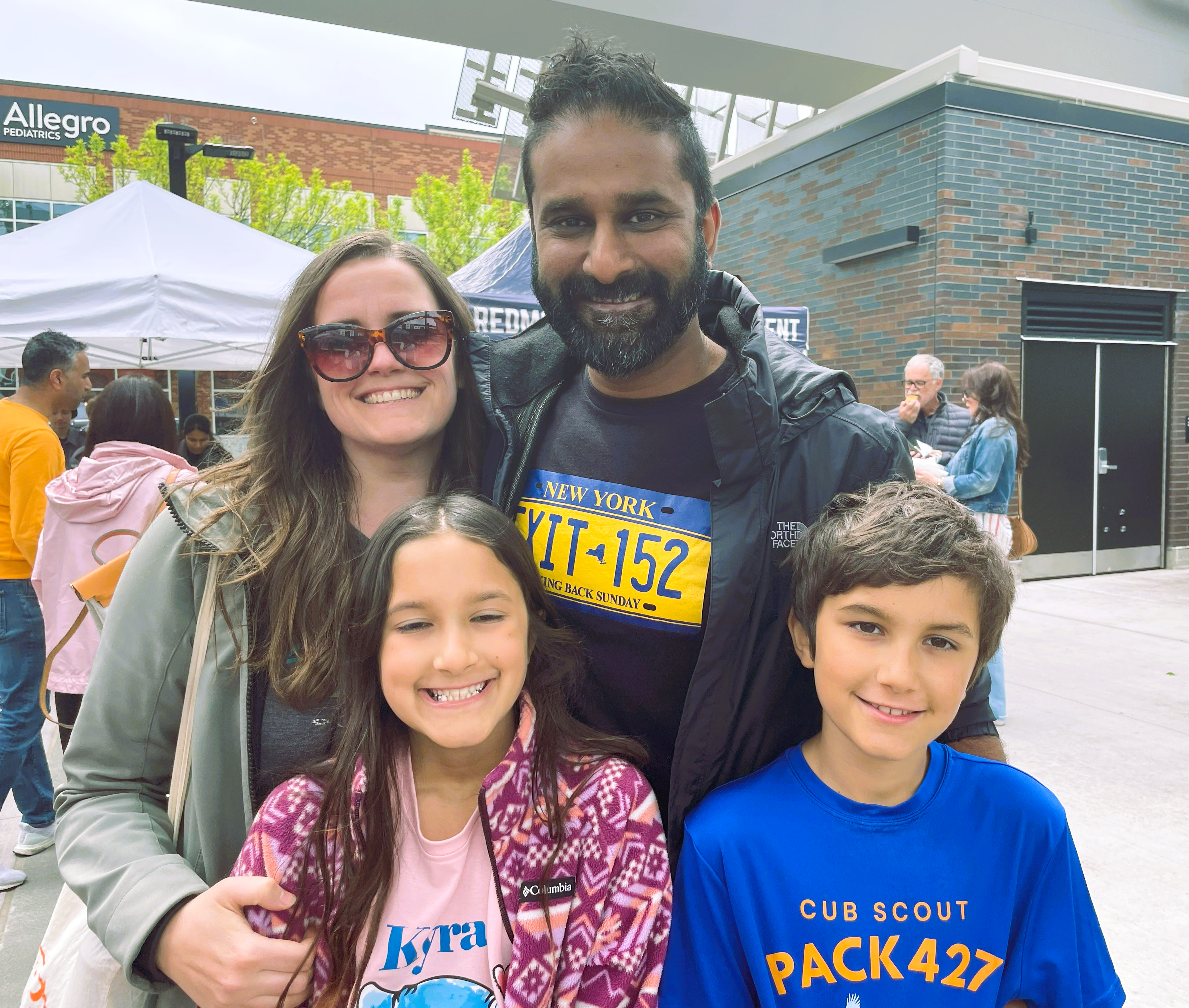 VijayLizFamily-Downtown-Redmond A family of four -- man woman, son, and daughter, smile for the camera.