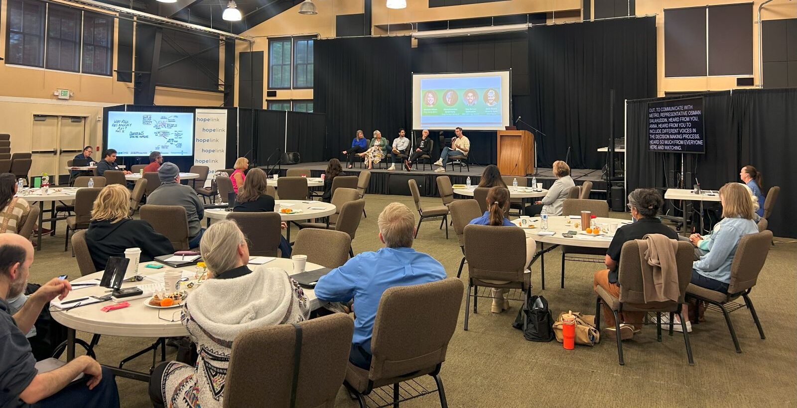 Participants listen to a panel of speakers onstage.