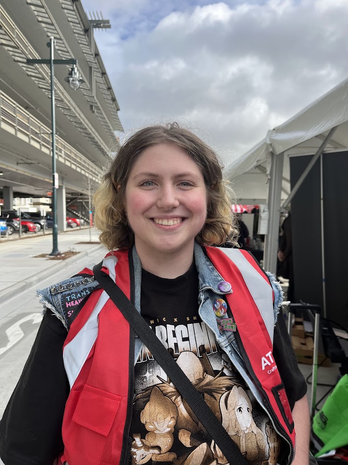 A smiling person in a red vest and black shirt