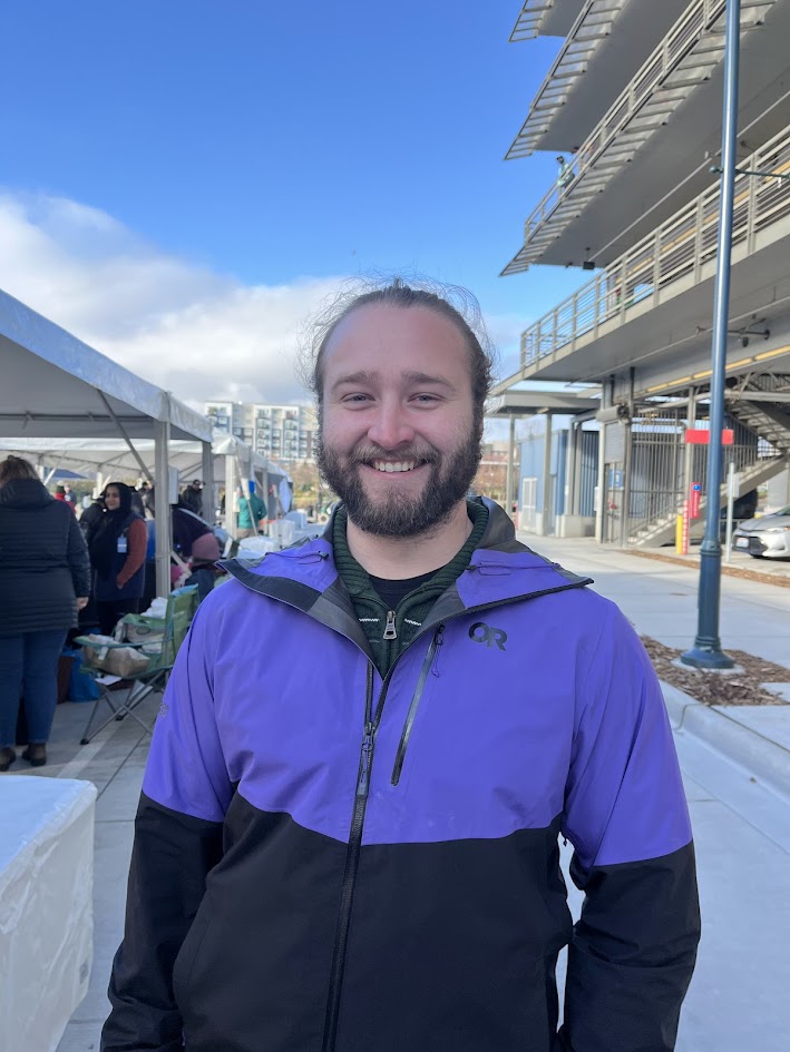 A smiling man in a purple and black jacket