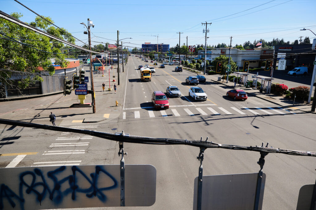 An image taken from an overpass looking down on a street intersection on Aurora Avenue. Crosswalks and 4 lanes of traffic are in the background.
