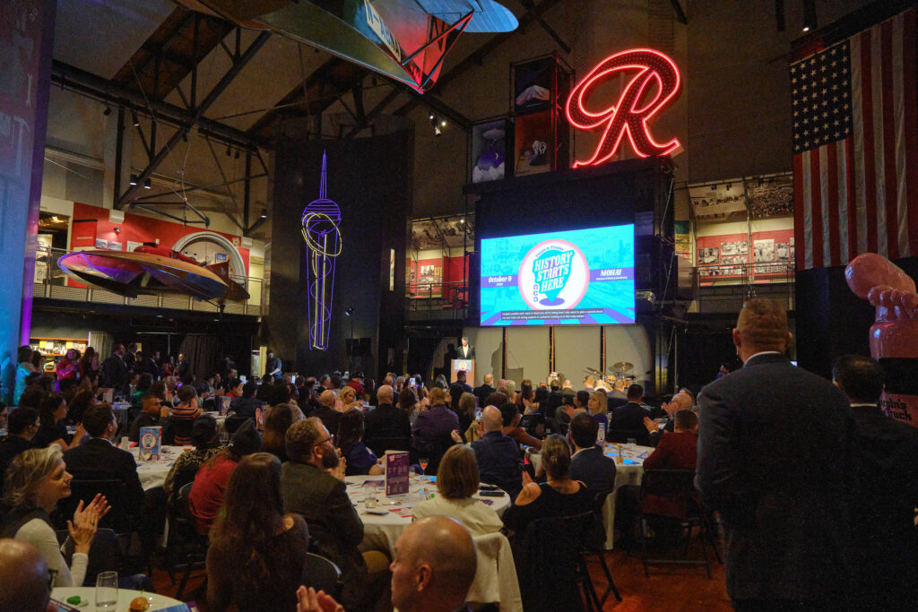A crowd gathers for the program in the atrium of MOHAI for Tuxes & Trains 2026.