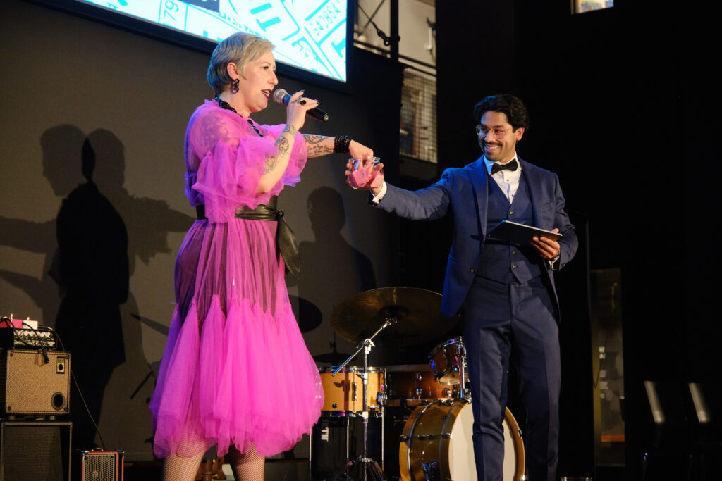Emcee Sasha Summer Cousineau draws a raffle ticket from a bowl held by co-emcee Rep. Osman Salahuddin.